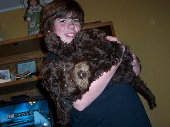 A young person holding a fluffy brown puppy.