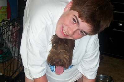 A person in a white t-shirt hugging a dog.